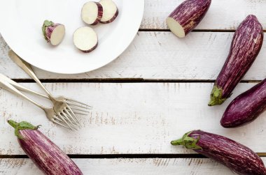 Bütün ve dilimlenmiş patlıcan, Gandia 'nın beyaz bir tabakta, çatallı, beyaz arka planda listelenmiş.. 