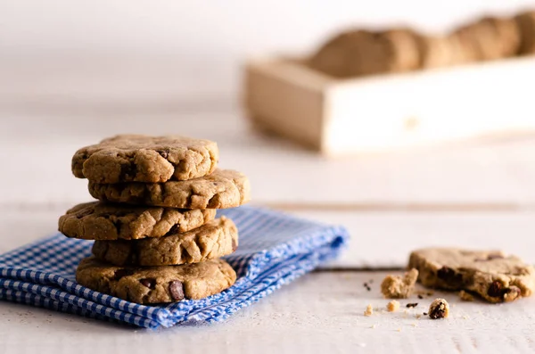 白と青のナプキンに積み上げられたバニラとチョコレートクッキー 白い木製の背景に木製の箱にかまれたクッキーとクッキー — ストック写真