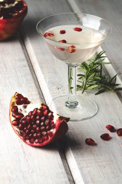 Bir bardaktaki nar suyu, nar ve biberiye yapraklarıyla beyaz ahşap bir zemin üzerinde.. 