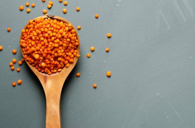 Ahşap kaşıkta kırmızı mercimek açık mavi arka planda. 