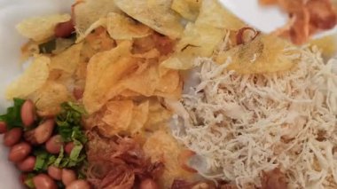 Bir kase sıcak bubur ayam dilimlenmiş tavuk, kraker ve lezzetli malzemelerle, kahvaltı ya da rahatlatıcı bir yemek için mükemmel olur..