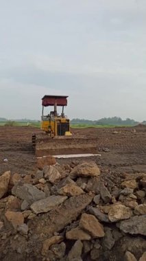 İnşaatın ilk aşamalarını desteklemek ve bölgeyi inşaat faaliyetlerine hazırlamak için toprağı ve zemini düzleştirmek üzere inşaat sahasında bir buldozer faaliyet gösteriyor..