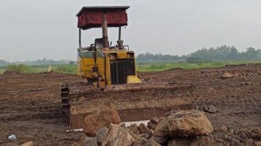 İnşaatın ilk aşamalarını desteklemek ve bölgeyi inşaat faaliyetlerine hazırlamak için toprağı ve zemini düzleştirmek üzere inşaat sahasında bir buldozer faaliyet gösteriyor..