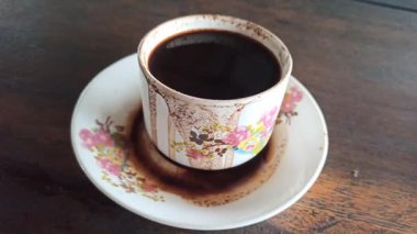 Klasik bir bardakta servis edilen koyu bir fincan, zengin bir aroma ve basit bir geleneksel stil, rahatlatıcı bir an ve günlük rutin için mükemmel..