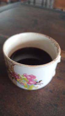 Klasik bir bardakta servis edilen koyu bir fincan, zengin bir aroma ve basit bir geleneksel stil, rahatlatıcı bir an ve günlük rutin için mükemmel..