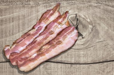 Three Belly Bacon Rashers On Old Rough Wooden Surface