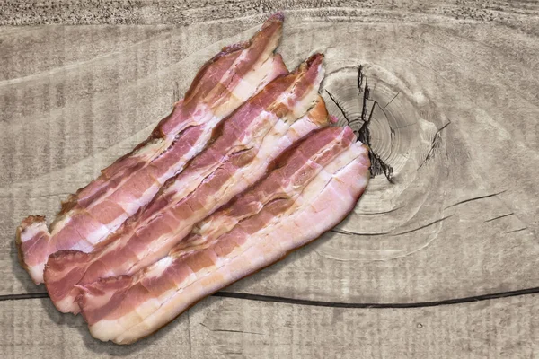 Three Belly Bacon Rashers On Old Rough Wooden Surface — Stok fotoğraf