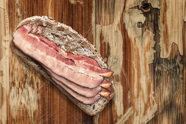 Bread Slice with Bacon Rashers on Old Wooden Background — Stockfoto