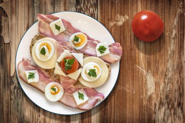 Plate with Bacon Cheese Egg Ham and Tomato Sandwich on Old Wooden Background