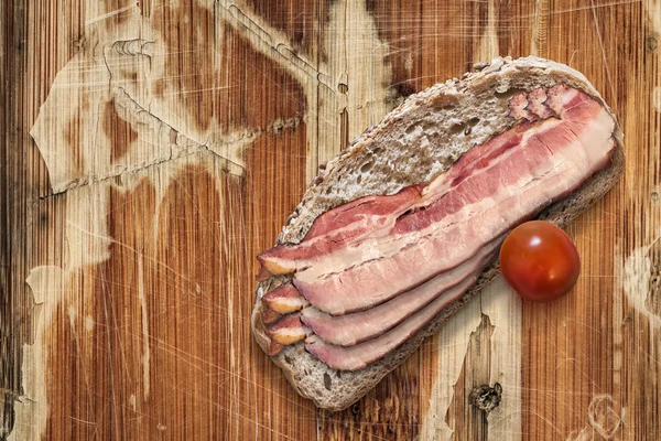 Бекон с помидорами вишни и слайсами хлеба на старом вудском фоне — стоковое фото