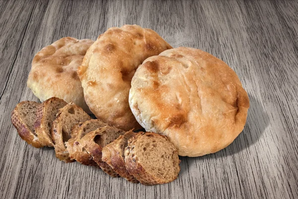 Placa de rebanadas integrales de pan de baguette con mocasines de pan de pita en mesa de madera —  Fotos de Stock