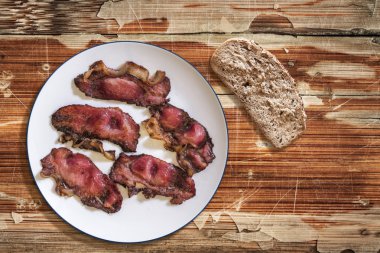Plate of Fried Pork Ham Rashers and slice of Integral Bread on old Wooden Table