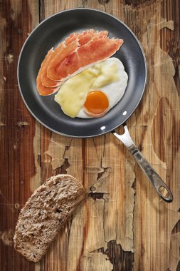 Prosciutto Rashers sahanda yumurta ve peynir ekmek dilimi eski tavada ahşap masa kırık