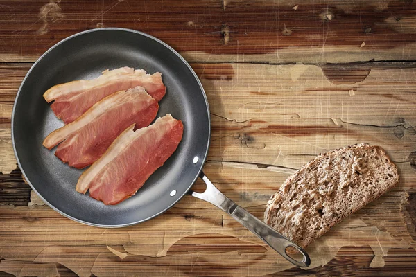 Fried Pork Ham rashers in Teflon Frying Pan with slice of Integral Bread on old Wooden Table — Stockfoto