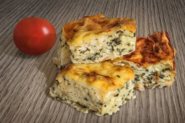 Torta de espinafre de queijo Fatias Zeljanica com conjunto de tomate na superfície da mesa de madeira — Fotografia de Stock