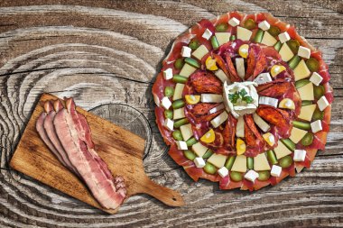 Appetizer Meze with Bacon Rashers on Cutting Board on Old Wood Background clipart