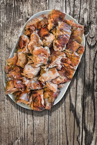 Bord van Spit geroosterd varkensvlees segmenten op oude houten achtergrond — Stockfoto