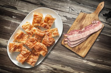 Peynir pasta Gibanica ve kesme tahtası domuz pastırma Rashers Set eski ahşap Bahçe masa yüzeyi ile tabağı