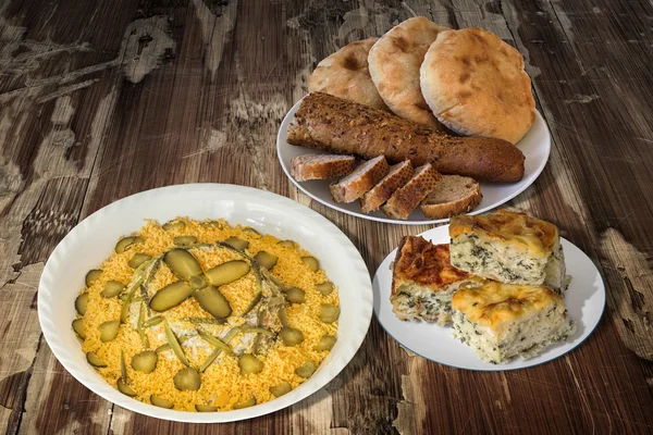 Ensalada rusa con pan y tarta de queso de espinacas en una mesa de madera vieja agrietada — Foto de Stock