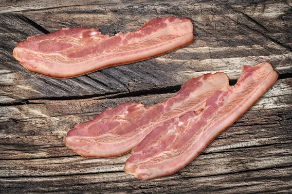 Varkensvlees spekreepjes op oude geknoopt gekraakt hout achtergrond — Stockfoto
