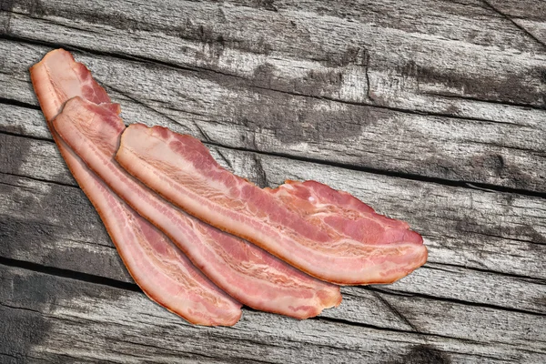 Rashers au bacon de porc sur fond de vieux bois craquelé noué — Photo
