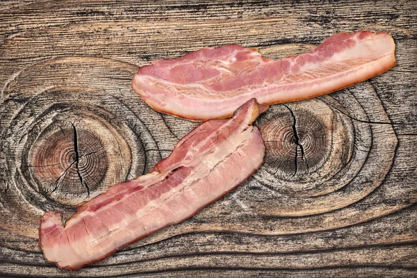 Varkensvlees spekreepjes op oude geknoopt gekraakt hout achtergrond — Stockfoto