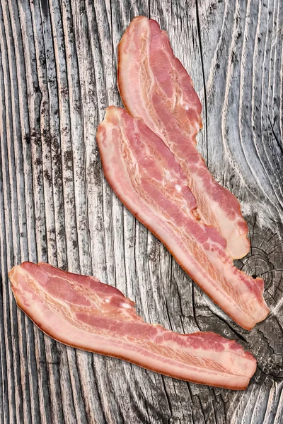 Maiale bacon rasher su vecchio incrinato annodato legno fondo — Foto Stock