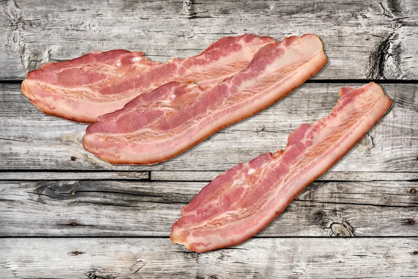 Rasher di pancetta di maiale su sfondo di legno vecchio annodato — Foto Stock