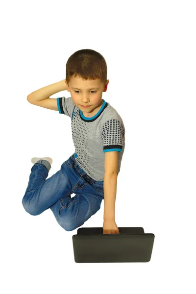 Junge mit Laptop denkt auf den Knien sitzend Stockfoto