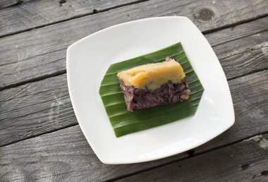 Tay tatlı, yapışkan pirinç ve yumurta muhallebi krem bir plaka üzerinde muz yaprak, sarma,