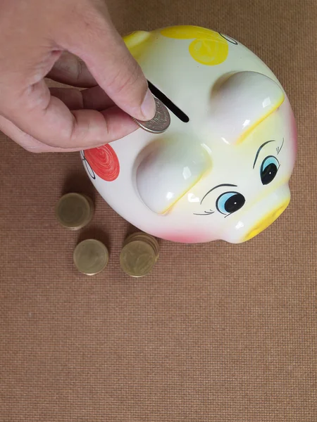 Colocando moeda em pequeno banco porquinho — Fotografia de Stock