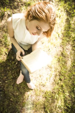 Kitap, bir yeşil çimenlerin üzerinde oturan kız yakın çekim