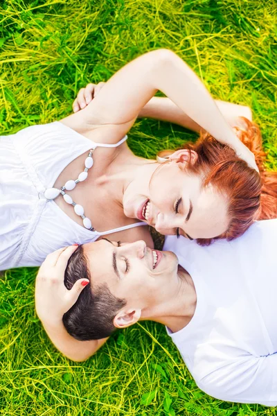 向上查看 在公园里躺在绿草上的一对快乐的年轻夫妇的肖像 — 图库照片