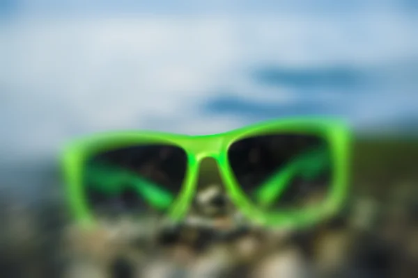 Gafas de sol verdes sobre guijarro — Foto de Stock