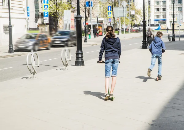 Meisje en jongen rijden kick scooters — Stockfoto