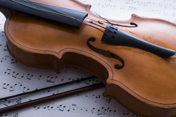 Скрипка и лук на столе — стоковое фото