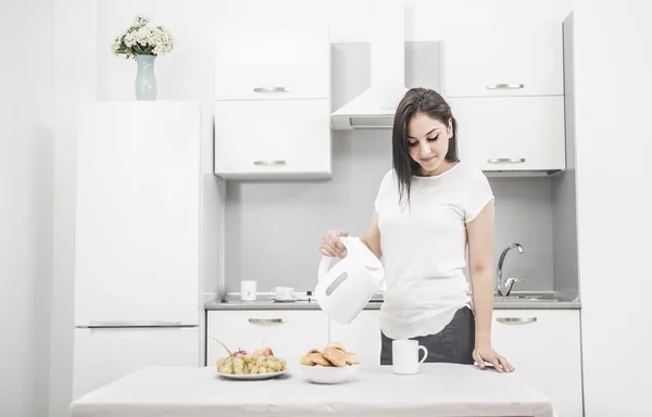 Mujer con hervidor en la mano de pie en la cocina — Foto de Stock