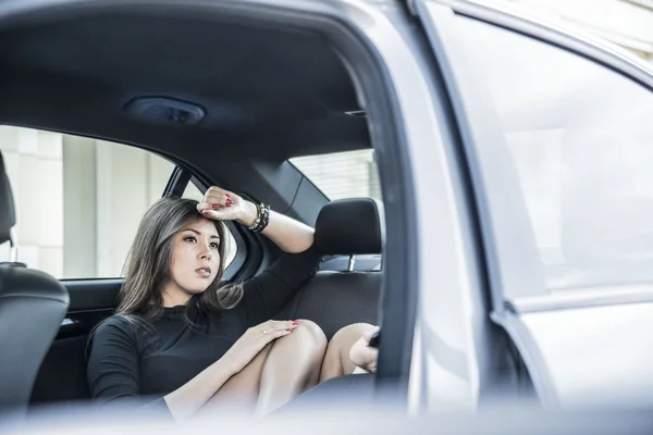 Brunette woman sitting on back seat — Stock Photo, Image