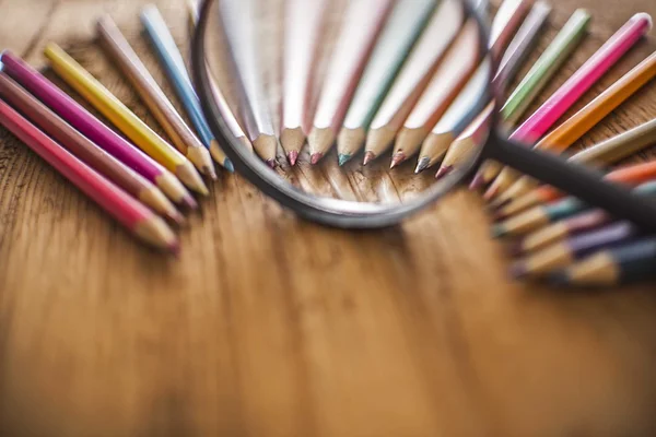 Pencils under magnifying glass — Stock Photo, Image