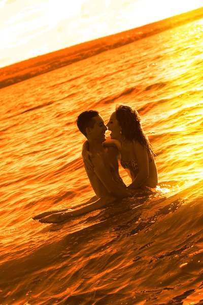 夕暮れ時水に立っている若い大人恋人 — ストック写真