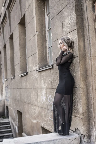 Terk edilmiş eski beton duvarın yanında duran genç ve güzel Beyaz bir kadının portresi 