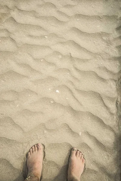 Barefoot foots standing on yellow sand — Stock Photo, Image
