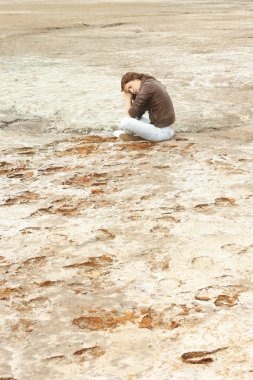 deri ceket, kot arka plan boş çöl arazi üzerinde giyen üzgün kadın. Rüya gibi genç yetişkin kız aşağı bakıyor