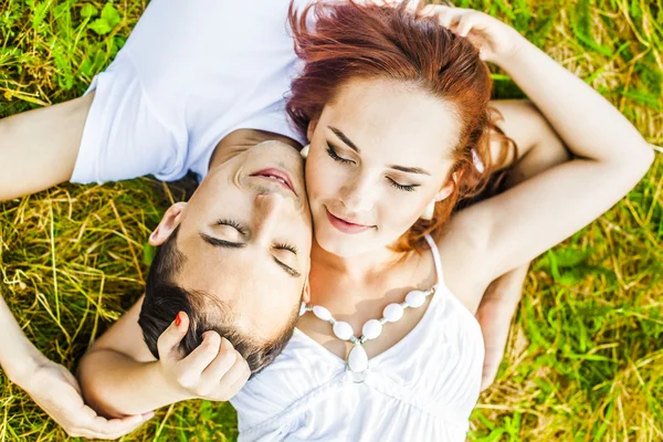 向上查看 Portrarit 的一对幸福的年轻夫妇躺在草地上的公园 — 图库照片