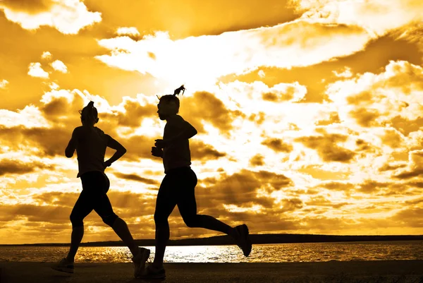 Дві жінки біжать на заході сонця — стокове фото
