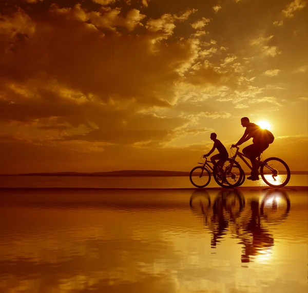 Siluety cyklistů na pobřeží. — Stock fotografie