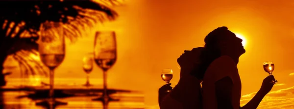 Silhouettes of Man and woman drink  champagne  at sunset