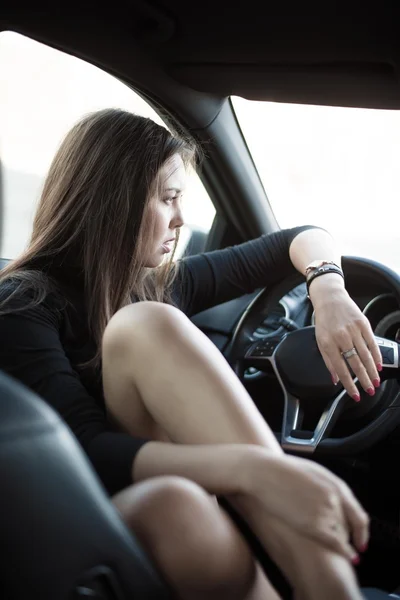 Mulher sentada em carro preto de luxo — Fotografia de Stock