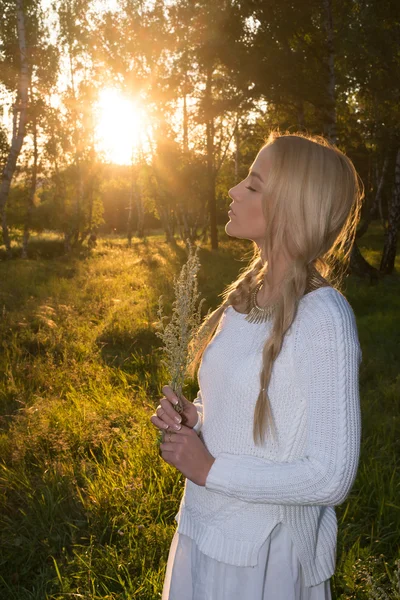 Menina em um campo segurando flores — Fotografia de Stock