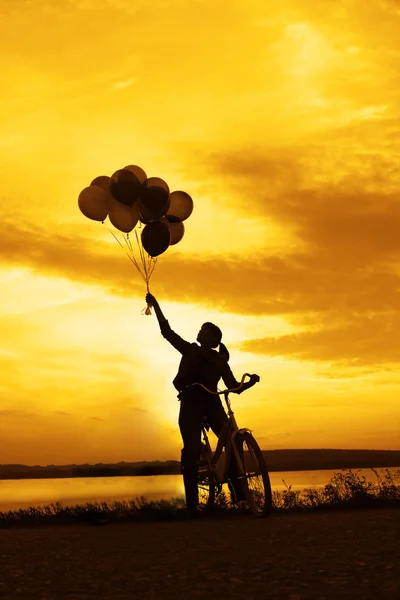 Chica en bicicleta celebración de globos de aire — Foto de Stock